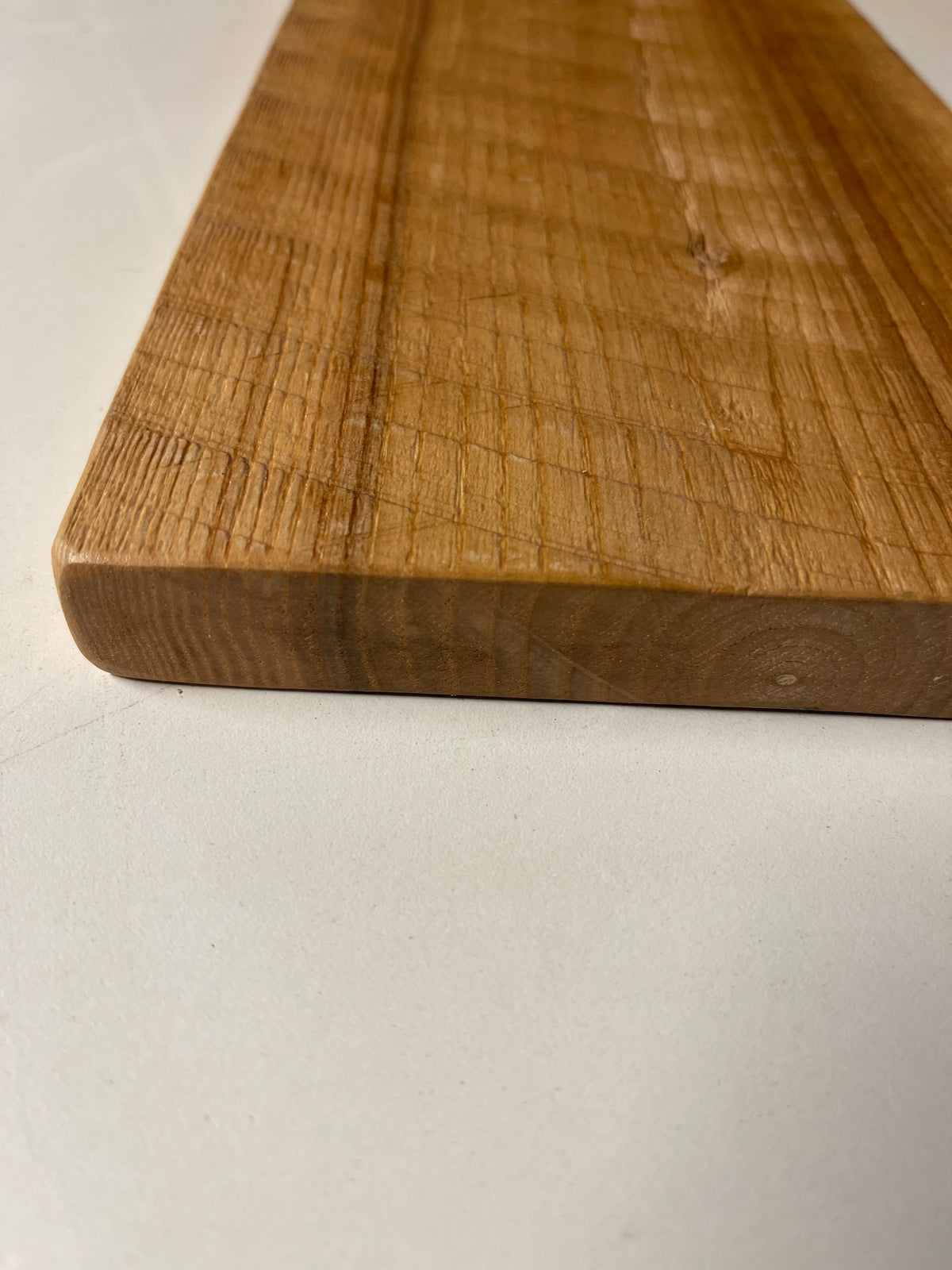 A close-up image of a solid ash wall board with a natural finish, displaying unique grain patterns and saw marks.